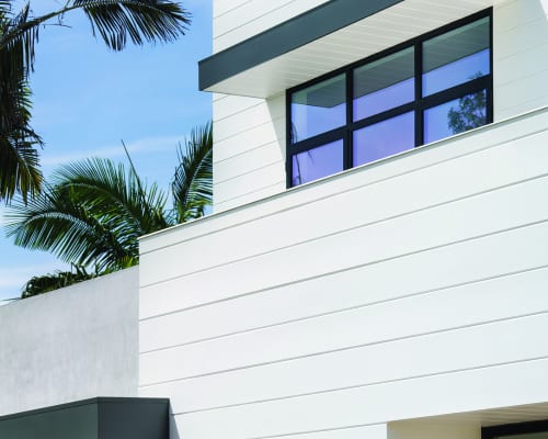 White horizontal siding trim on a modern house corner, showing clean lines and shadow depth under bright daylight.