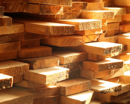 Fire-resistant treated lumber stacked in a warm, sunlit arrangement showing grain and texture.