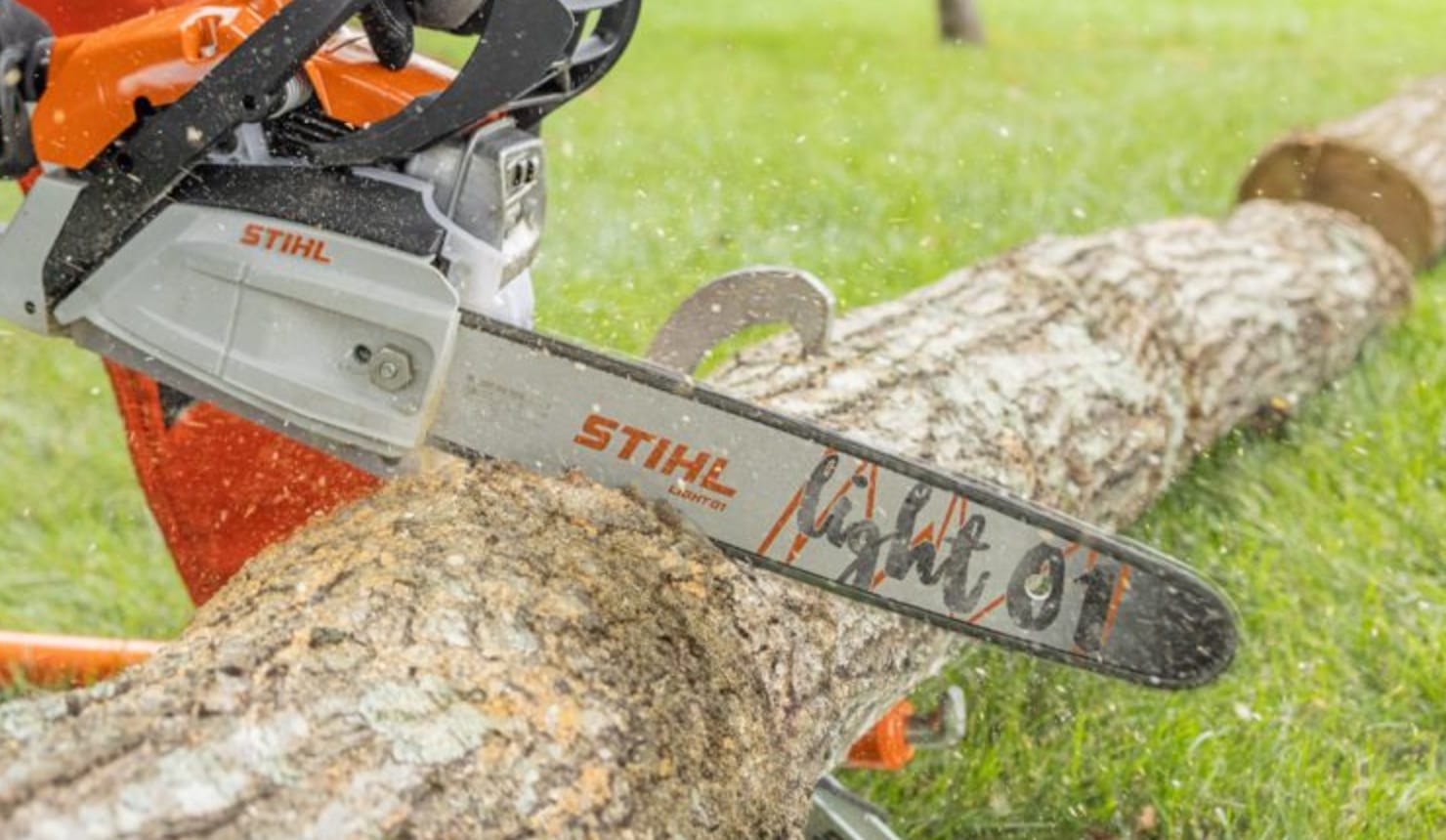 Stihl chainsaw cutting through a log, with the "Light 01" model name visible on the guide bar.